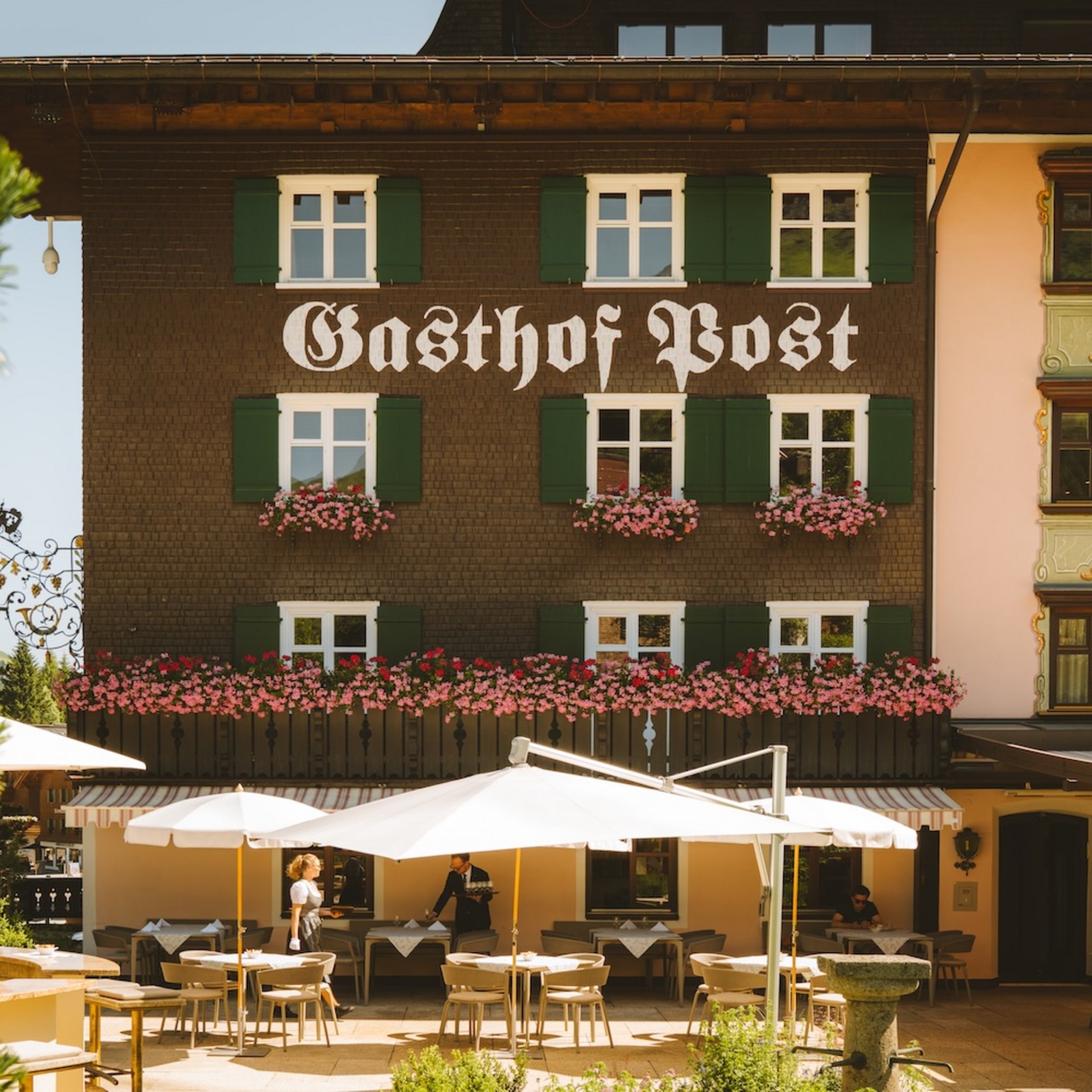 Dining at Hotel Post Lech | Restaurant in Lech Facade of Gasthof Post with outdoor terrace and white umbrellas