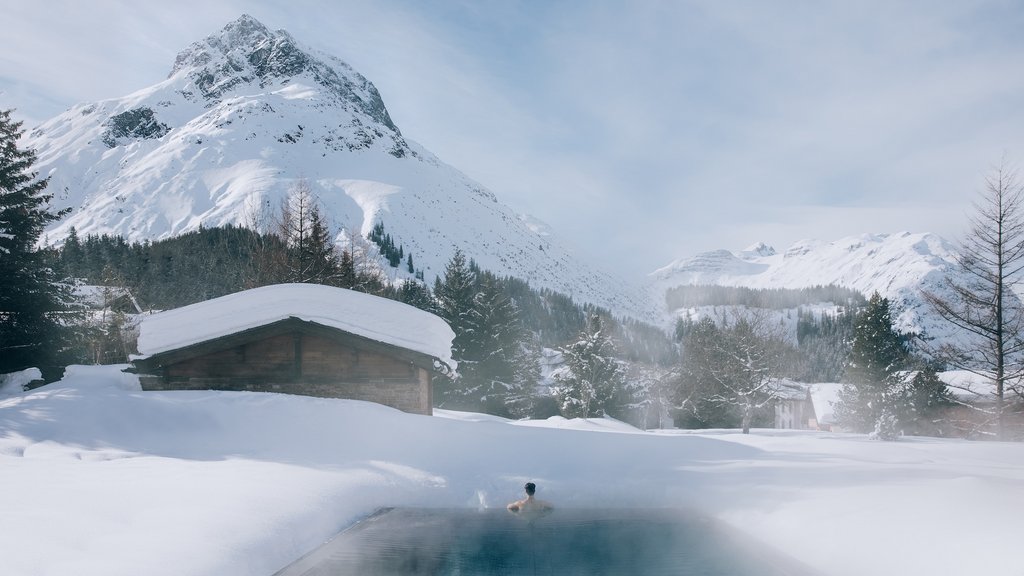 Hotel Post Lech am Arlberg Person relaxing in heated outdoor pool with snowy mountain landscape