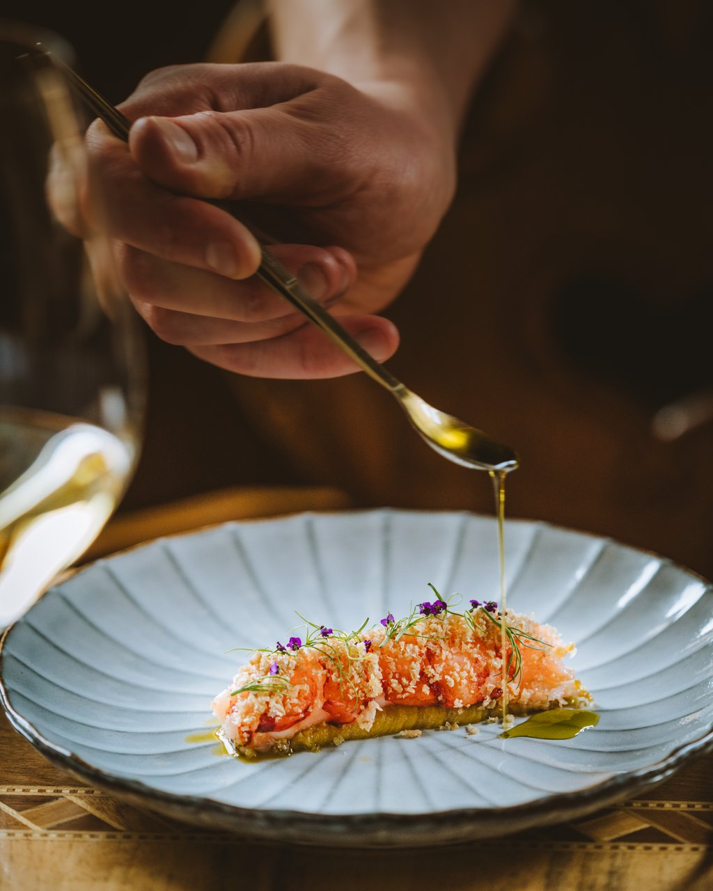 Hotel Post Lech am Arlberg Hand drizzling oil over a plated dish with salmon and herbs