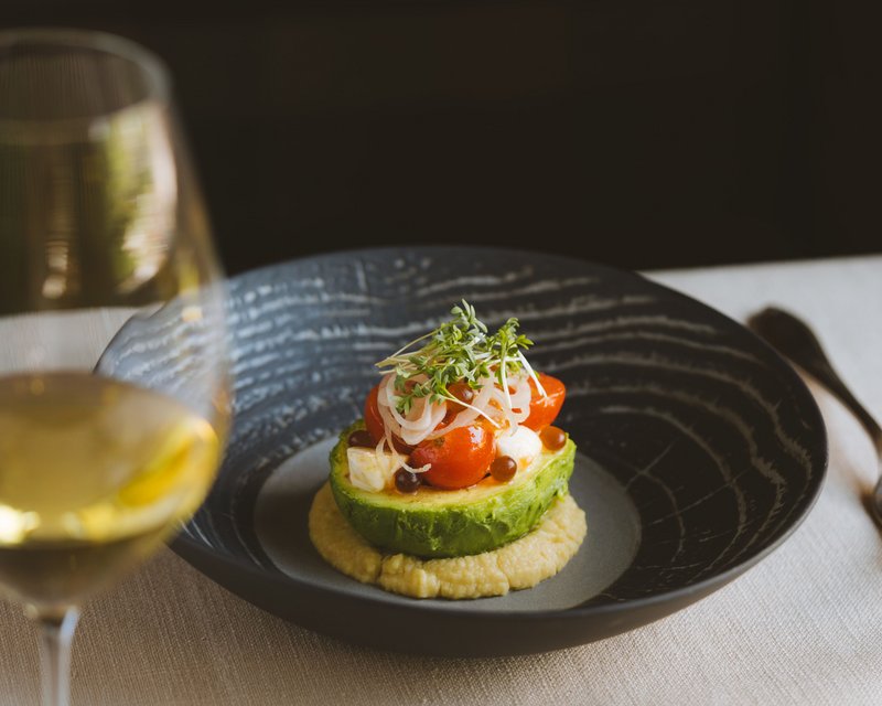 Neues aus der Post Avocadohälfte mit Kirschtomaten, Zwiebeln und Kresse auf cremigem Dip