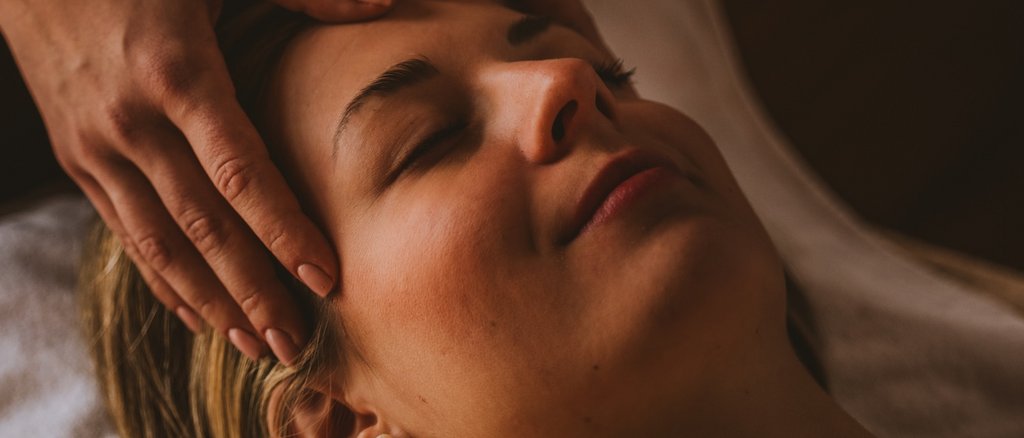 Day Spa im Hotel Post Lech Frau erhält entspannende Gesichtsmassage bei gedämpftem Licht