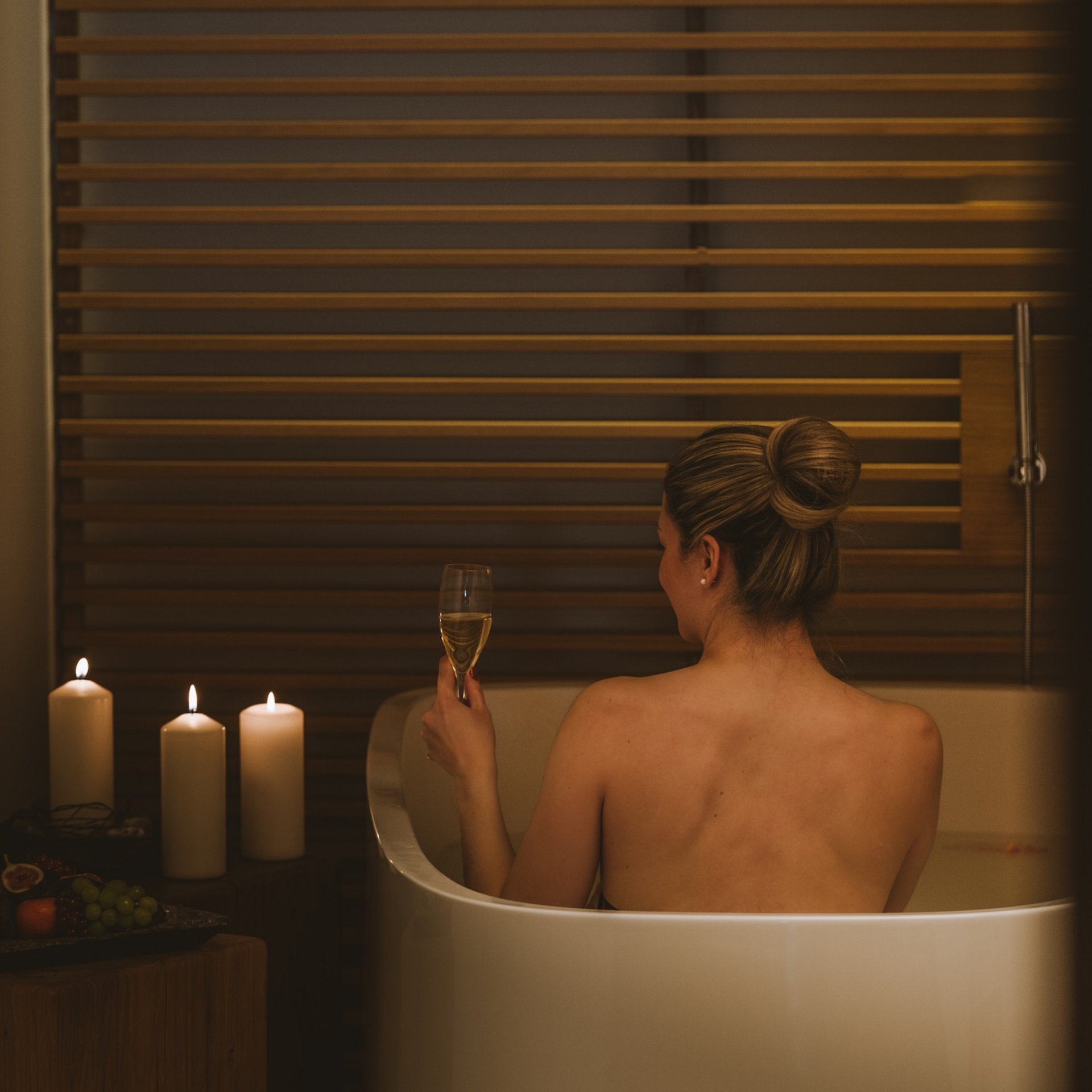 Day Spa im Hotel Post Lech Frau entspannt in der Badewanne mit Kerzen und einem Glas Wein