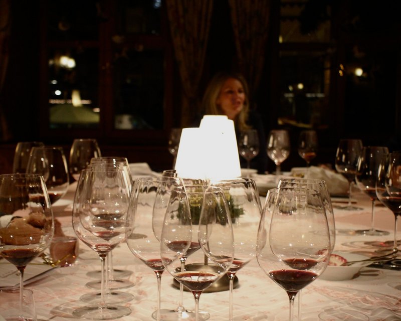 Neues aus der Post Weingläser mit rotem Wein auf einem gedeckten Tisch bei gedimmtem Licht