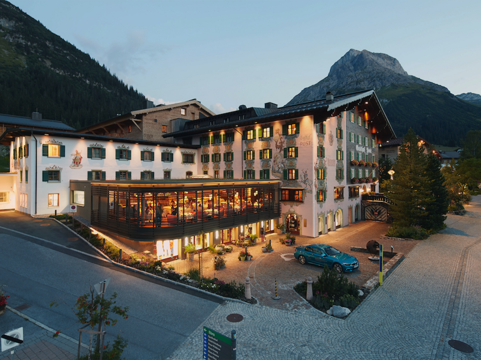 Impressions Hotel building with lit restaurant and mountain backdrop at dusk
