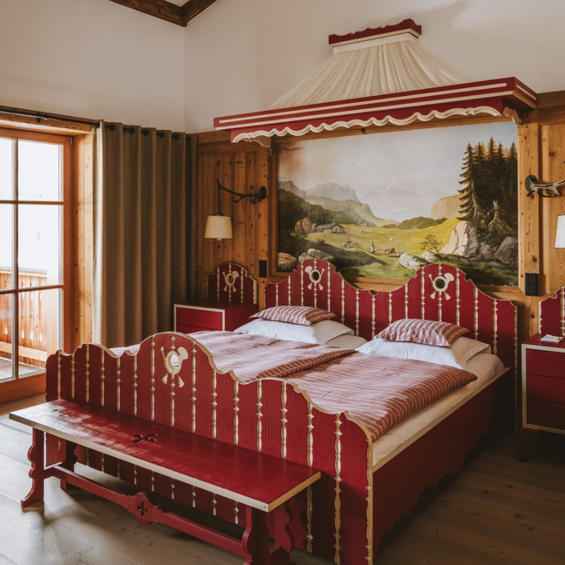 5-Sterne Hotel Post Lech Rustikales Schlafzimmer mit rotem Doppelbett, Holzvertäfelung und Landschaftsgemälde