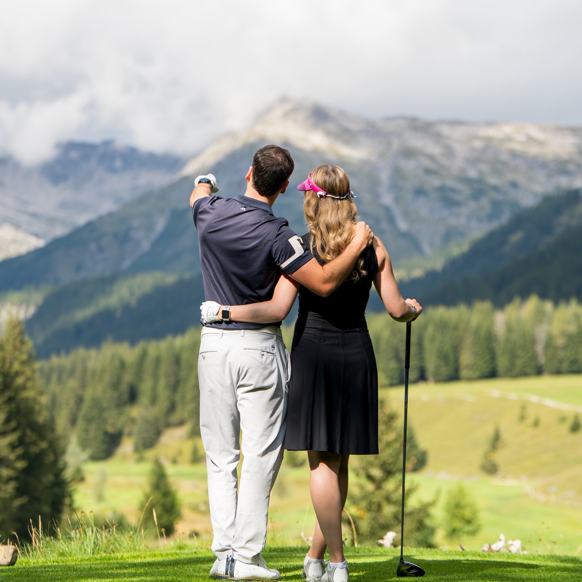 Sommer am Arlberg Paar auf Golfplatz umarmt sich und blickt auf Berge und Landschaft