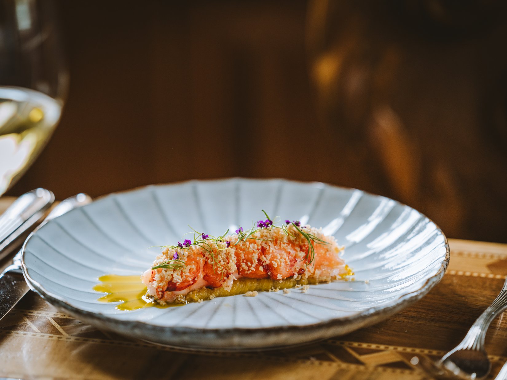 Impressions Delicately plated shrimp with sauce and edible flowers on a white plate