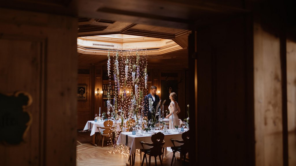 Events in Lech | Hotel Post Lech Arlberg Bride and groom at wedding table with string lights in cozy wooden room